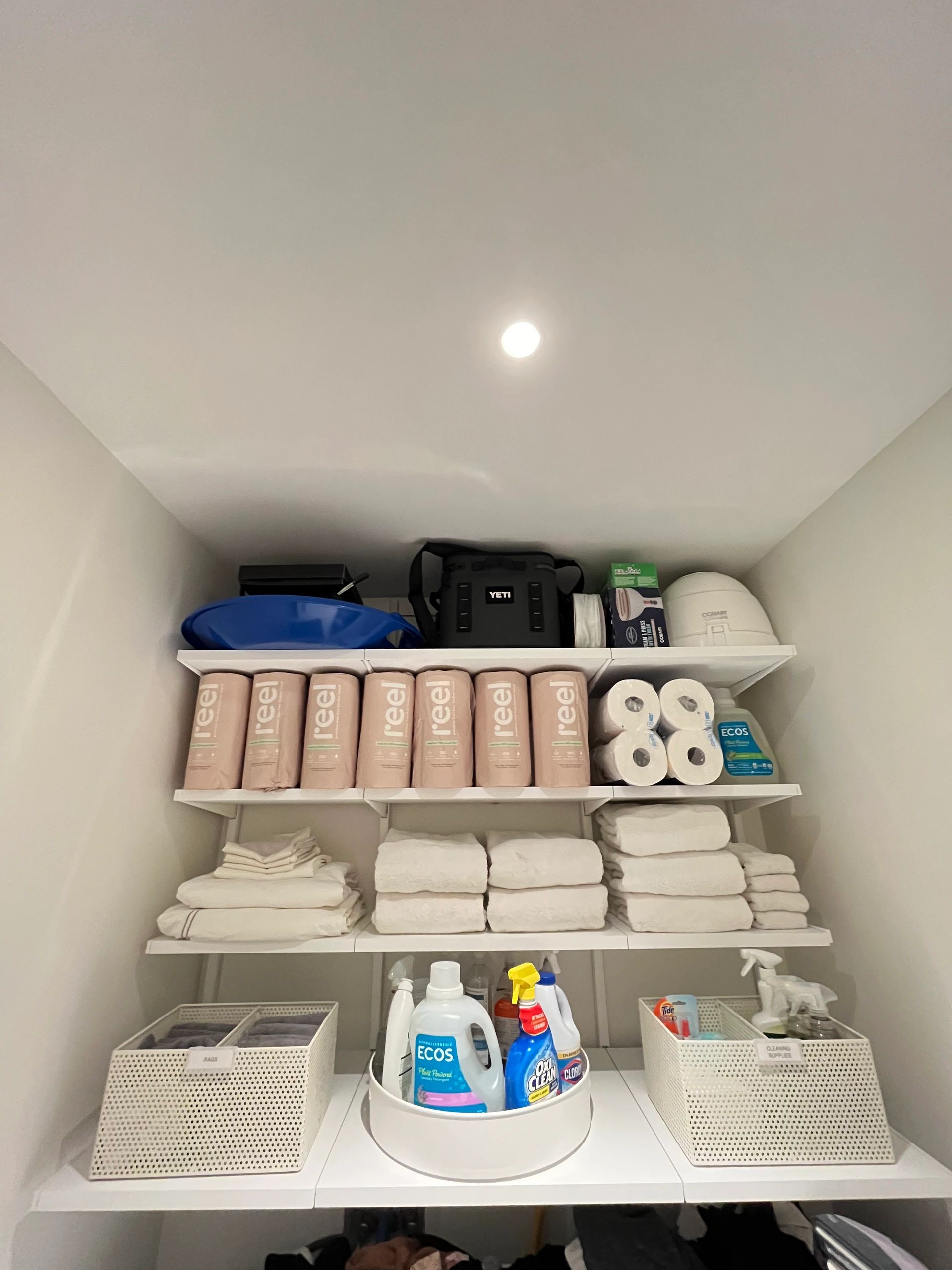 Organized linen closet with towels and cleaning supplies