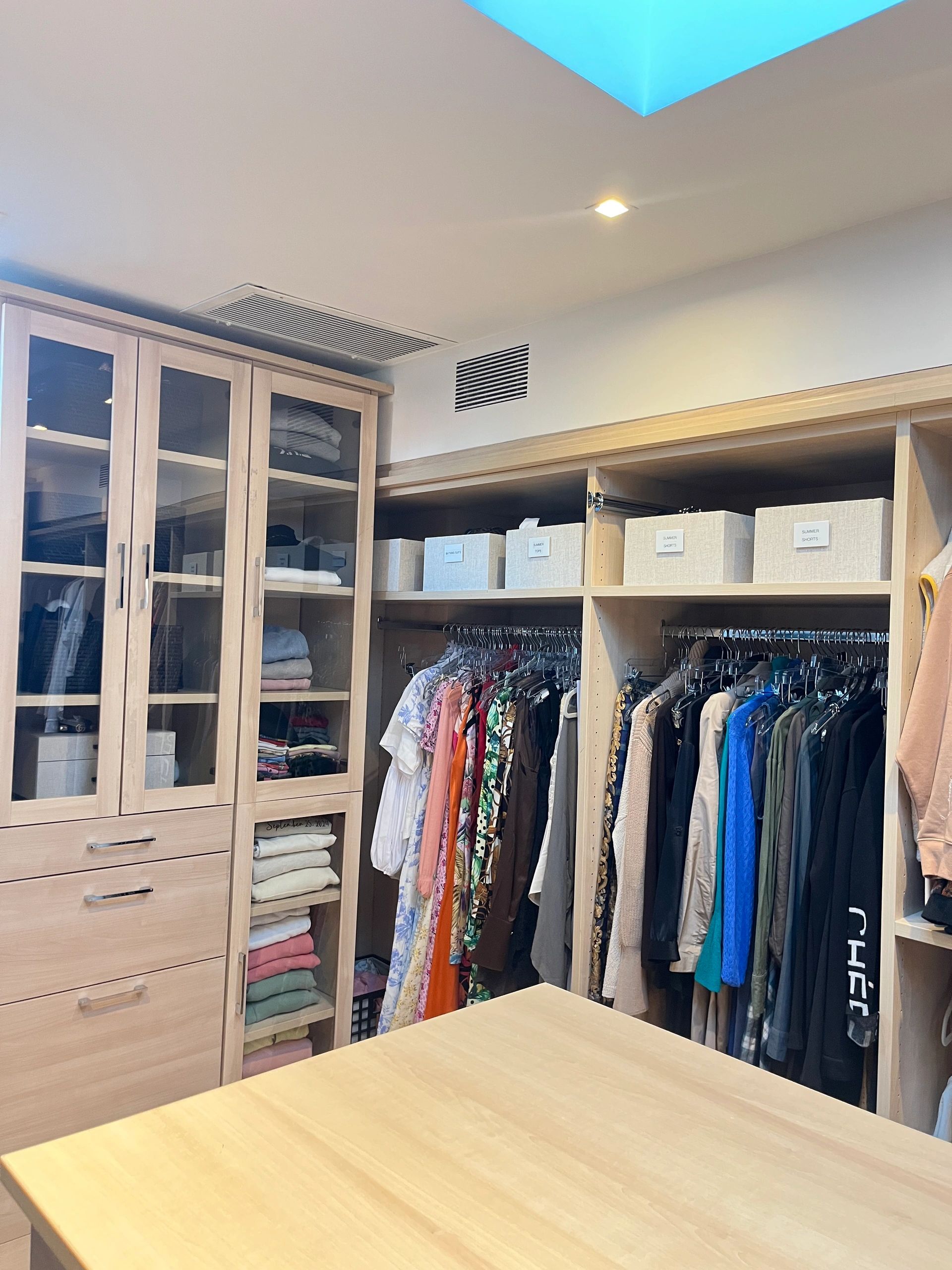 Walk-in closet with light wood cabinetry